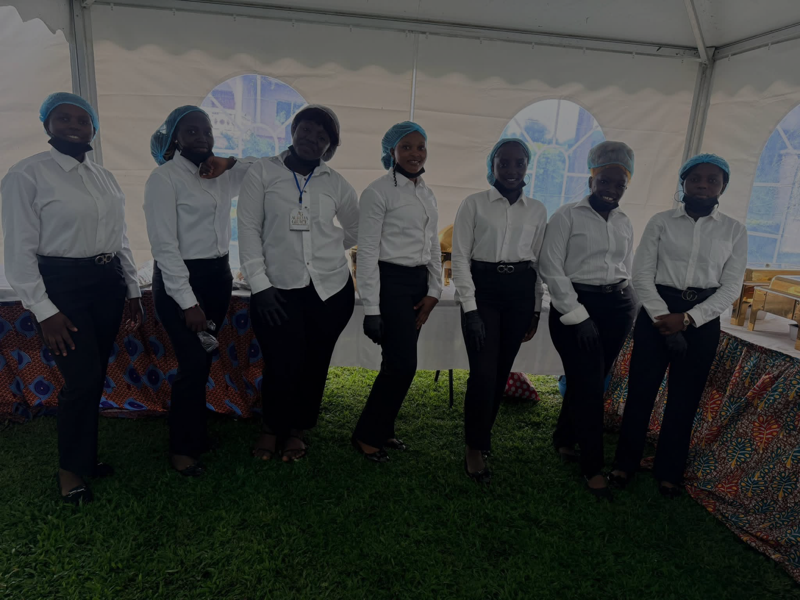 The Aurelia Grace hostess team standing together at a corporate event in Buea, dressed in matching white shirts and black trousers.